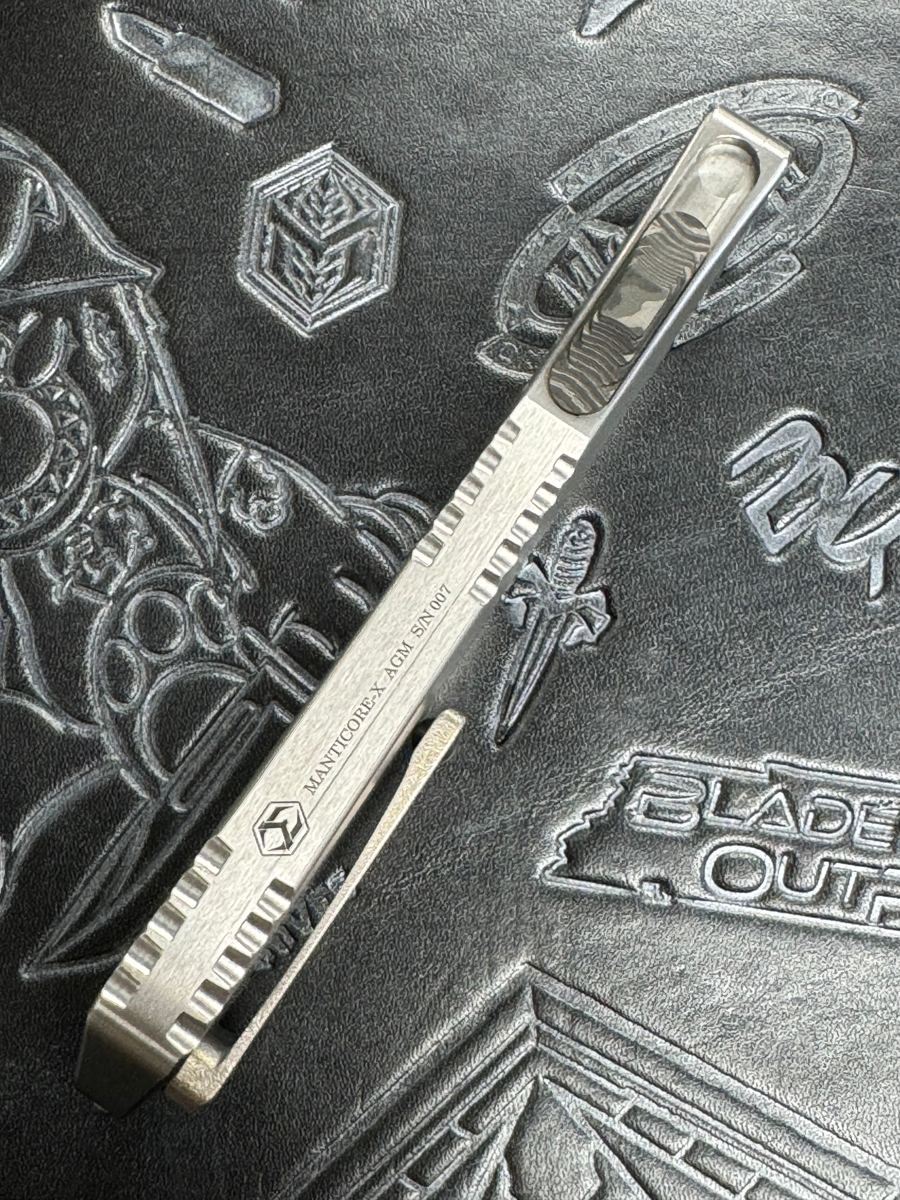 Pre Owned Heretic Knives Custom Manticore X D/E Hand Ground Vegas Forged Damascus, Hefted Stainless Steel Handle, Orange Peel Clip, Deep Engrave Logo, Carbon Fiber Button SN:007