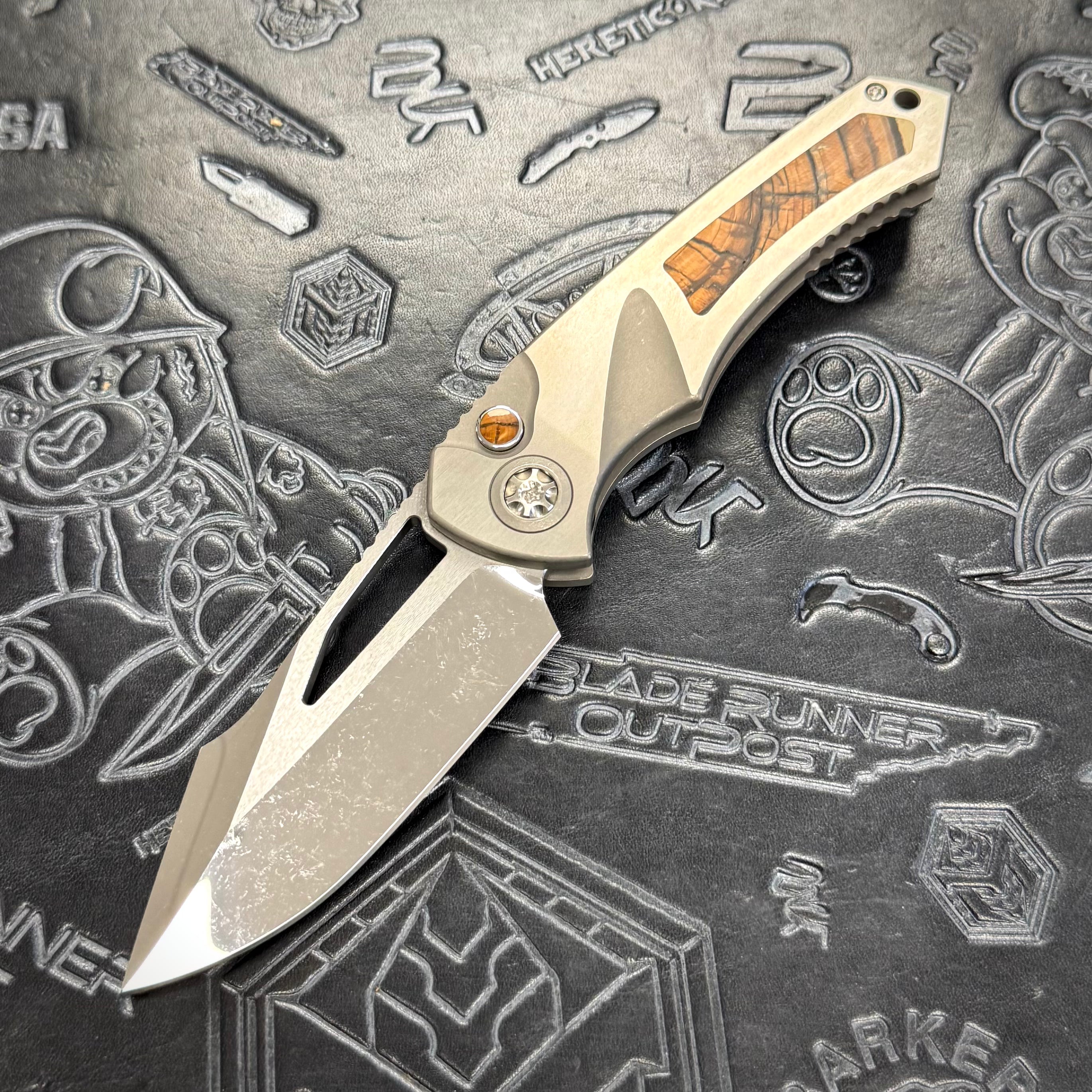 Heretic Pariah Manual Custom - Single Cracked Ice - Hefted
Titanium Chassis w/ Brown
Mammoth Inlays & Brown Mammoth button inlay S/N: 012