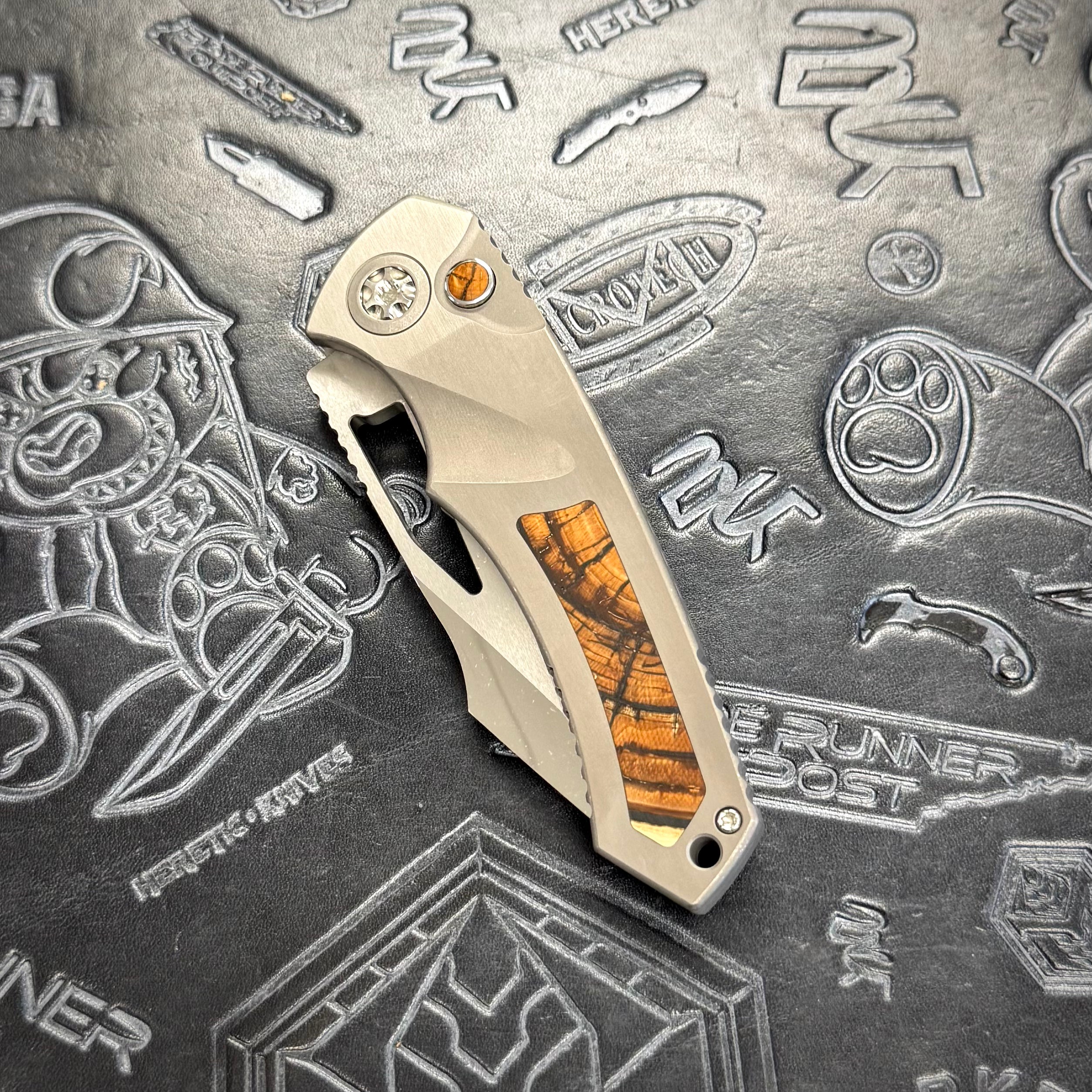 Heretic Pariah Manual Custom - Single Cracked Ice - Hefted
Titanium Chassis w/ Brown
Mammoth Inlays & Brown Mammoth button inlay S/N: 012