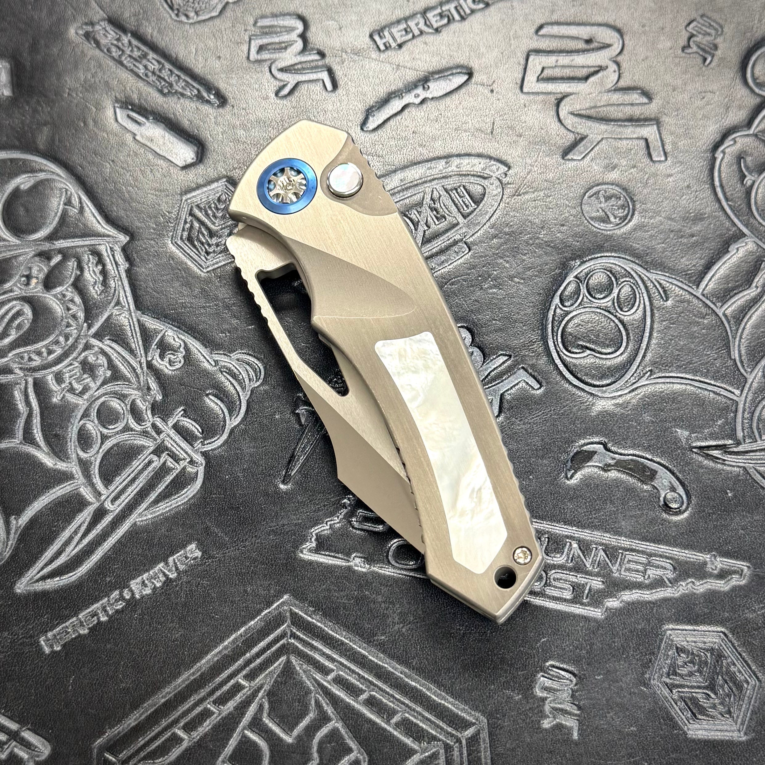 Heretic Pariah Manual Custom - Single Edge Mirror Polish - Hefted Titanium Chassis w/ Mother of Pearl inlays & Mother of Pearl button inlay - Blue Ti pivot collars
S/N: 022