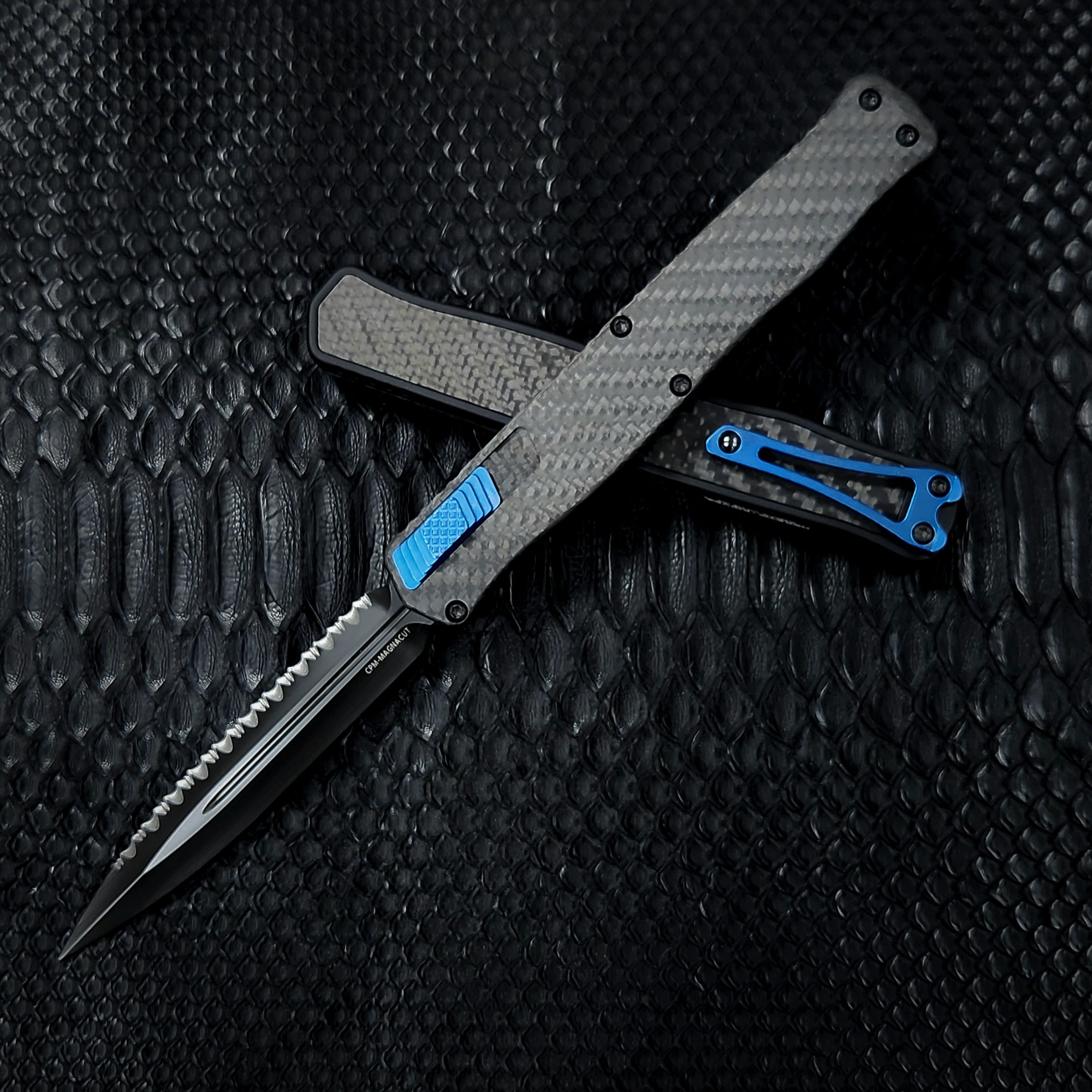 Heretic Knives Cleric II - Black ANO Chassis w/ Carbon Fiber inlay, Carbon Fiber Top Cover, DLC Double Edge FULL SERRATED Magnacut blade, Blue Ti Button and Blue Ti Clip H020-6C-CF/BLU *